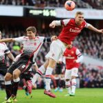 Per Mertesacker and Steven Gerrard both challenge for the ball as Martin Skrtel looks on the Gunners won the game 2-1
