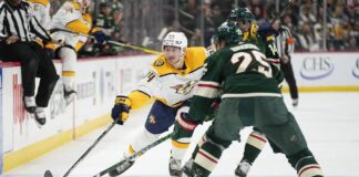 Nashville Predators left wing Tanner Jeannot, left, reaches for the puck next to Minnesota Wild defenseman Jonas Brodin (25) during the second period of an NHL hockey game Sunday, Feb. 19, 2023, in St. Paul, Minn.