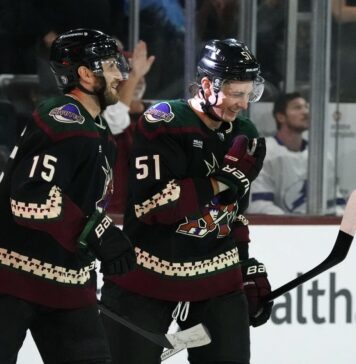 Arizona Coyotes defenseman Troy Stecher (51) and Coyotes center Alexander Kerfoot (15) celebrate a goal by Coyotes' Michael Carcone against the Tampa Bay Lightning during the first period of an NHL hockey game Tuesday, Nov. 28, 2023, in Tempe, Ariz. (AP Photo/Ross D. Franklin)