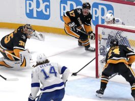 Tampa Bay Lightning's Brayden Point, top right behind goal, gets the game-winning overtime goal past Pittsburgh Penguins goaltender Tristan Jarry (35) and defenders Sidney Crosby (87) and Matt Grzelcyk (24) during an NHL hockey game Tuesday, Nov. 19, 2024, in Pittsburgh. The Lightning won 3-2. (AP Photo/Gene J. Puskar)