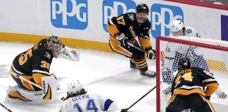 Tampa Bay Lightning's Brayden Point, top right behind goal, gets the game-winning overtime goal past Pittsburgh Penguins goaltender Tristan Jarry (35) and defenders Sidney Crosby (87) and Matt Grzelcyk (24) during an NHL hockey game Tuesday, Nov. 19, 2024, in Pittsburgh. The Lightning won 3-2. (AP Photo/Gene J. Puskar)