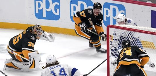 Tampa Bay Lightning's Brayden Point, top right behind goal, gets the game-winning overtime goal past Pittsburgh Penguins goaltender Tristan Jarry (35) and defenders Sidney Crosby (87) and Matt Grzelcyk (24) during an NHL hockey game Tuesday, Nov. 19, 2024, in Pittsburgh. The Lightning won 3-2. (AP Photo/Gene J. Puskar)