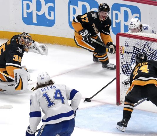 Tampa Bay Lightning's Brayden Point, top right behind goal, gets the game-winning overtime goal past Pittsburgh Penguins goaltender Tristan Jarry (35) and defenders Sidney Crosby (87) and Matt Grzelcyk (24) during an NHL hockey game Tuesday, Nov. 19, 2024, in Pittsburgh. The Lightning won 3-2. (AP Photo/Gene J. Puskar)