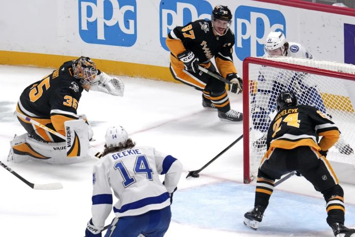 Tampa Bay Lightning's Brayden Point, top right behind goal, gets the game-winning overtime goal past Pittsburgh Penguins goaltender Tristan Jarry (35) and defenders Sidney Crosby (87) and Matt Grzelcyk (24) during an NHL hockey game Tuesday, Nov. 19, 2024, in Pittsburgh. The Lightning won 3-2. (AP Photo/Gene J. Puskar)