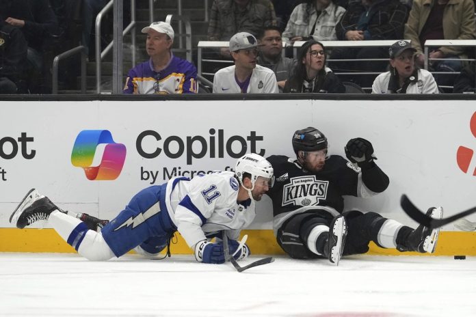 Tampa Bay Lightning center Luke Glendening, left, and Los Angeles Kings defenseman Vladislav Gavrikov fall as they vie for the puck during the first period of an NHL hockey game, Saturday, Jan. 4, 2025, in Los Angeles. (AP Photo/Mark J. Terrill)