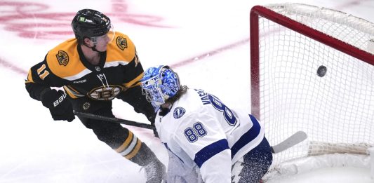 Boston Bruins center Trent Frederic (11) flips the puck past Tampa Bay Lightning goaltender Andrei Vasilevskiy (88) for a goal during the first period of an NHL hockey game, Tuesday, Jan. 14, 2025, in Boston. (AP Photo/Charles Krupa)