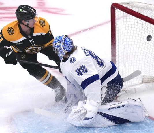 Boston Bruins center Trent Frederic (11) flips the puck past Tampa Bay Lightning goaltender Andrei Vasilevskiy (88) for a goal during the first period of an NHL hockey game, Tuesday, Jan. 14, 2025, in Boston. (AP Photo/Charles Krupa)