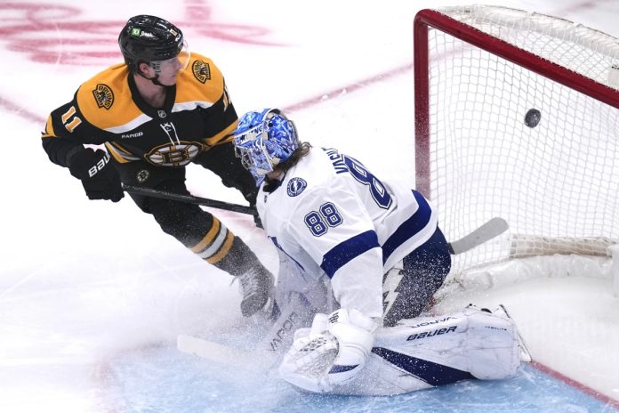 Boston Bruins center Trent Frederic (11) flips the puck past Tampa Bay Lightning goaltender Andrei Vasilevskiy (88) for a goal during the first period of an NHL hockey game, Tuesday, Jan. 14, 2025, in Boston. (AP Photo/Charles Krupa)