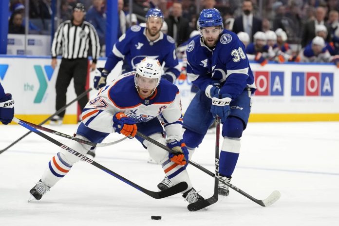 Edmonton Oilers center Connor McDavid (97) gets around Tampa Bay Lightning left wing Brandon Hagel (38) during the third period of an NHL hockey game Tuesday, Feb. 25, 2025, in Tampa, Fla. (AP Photo/Chris O'Meara)