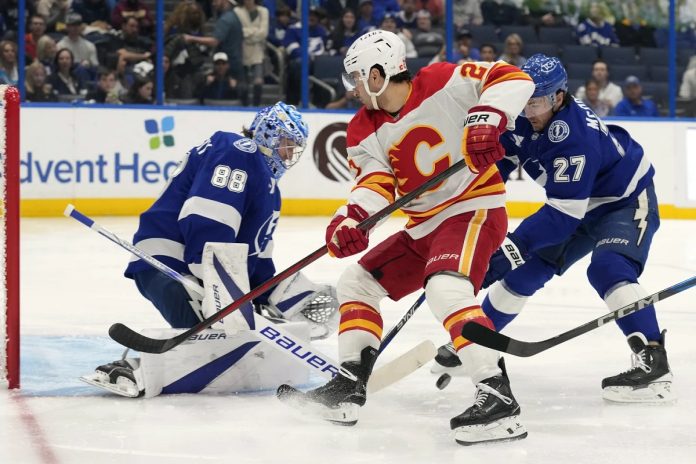 Tampa Bay Lightning goaltender Andrei Vasilevskiy (88) and defenseman Ryan McDonagh (27) team up to stop a shot by Calgary Flames right wing Matt Coronato (27, center) during the first period of an NHL hockey game Thursday, Feb. 27, 2025, in Tampa, Fla. (AP Photo/Chris O'Meara)