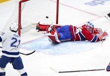 Tampa Bay Lightning's Brayden Point (21) scores against Montreal Canadiens goaltender Jakub Dobes, right, during second-period NHL hockey game action in Montreal, Sunday, Feb. 9, 2025. (Graham Hughes/The Canadian Press via AP)