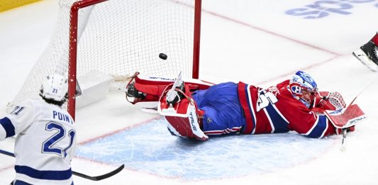 Tampa Bay Lightning's Brayden Point (21) scores against Montreal Canadiens goaltender Jakub Dobes, right, during second-period NHL hockey game action in Montreal, Sunday, Feb. 9, 2025. (Graham Hughes/The Canadian Press via AP)