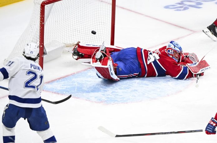 Tampa Bay Lightning's Brayden Point (21) scores against Montreal Canadiens goaltender Jakub Dobes, right, during second-period NHL hockey game action in Montreal, Sunday, Feb. 9, 2025. (Graham Hughes/The Canadian Press via AP)