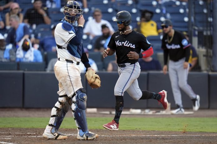 Miami Marlins' Otto Lopez scores in front of Tampa Bay Rays catcher Danny Jansen on an RBI single by Heriberto Hernandez off pitcher Garrett Cleavinger during the 10th inning of a baseball game Saturday, June 7, 2025, in Tampa, Fla. (AP Photo/Chris O'Meara)