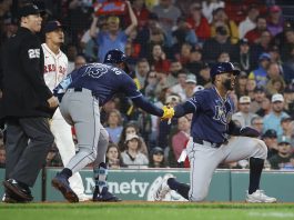 Tampa Bay Rays' Yandy Díaz is congratulated by teammate Junior Caminero (13) after scoring on a single by Jonathan Aranda during the seventh inning of a baseball game against the Boston Red Sox at Fenway Park, Monday, June 9, 2025, in Boston. (AP Photo/Mary Schwalm)