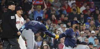 Tampa Bay Rays' Yandy Díaz is congratulated by teammate Junior Caminero (13) after scoring on a single by Jonathan Aranda during the seventh inning of a baseball game against the Boston Red Sox at Fenway Park, Monday, June 9, 2025, in Boston. (AP Photo/Mary Schwalm)