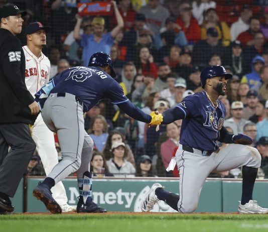 Tampa Bay Rays' Yandy Díaz is congratulated by teammate Junior Caminero (13) after scoring on a single by Jonathan Aranda during the seventh inning of a baseball game against the Boston Red Sox at Fenway Park, Monday, June 9, 2025, in Boston. (AP Photo/Mary Schwalm)