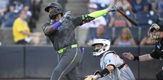 Tampa Bay Rays' Junior Caminero, left, watches the flight of the ball after hitting a three-run home run as Baltimore Orioles catcher Jacob Stallings and home plate umpire Sean Barber, right, look on during the first inning of a baseball game, Friday, July 18, 2025, in Tampa, Fla. (AP Photo/Phelan M. Ebenhack)