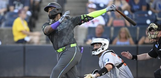 Tampa Bay Rays' Junior Caminero, left, watches the flight of the ball after hitting a three-run home run as Baltimore Orioles catcher Jacob Stallings and home plate umpire Sean Barber, right, look on during the first inning of a baseball game, Friday, July 18, 2025, in Tampa, Fla. (AP Photo/Phelan M. Ebenhack)