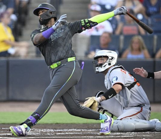 Tampa Bay Rays' Junior Caminero, left, watches the flight of the ball after hitting a three-run home run as Baltimore Orioles catcher Jacob Stallings and home plate umpire Sean Barber, right, look on during the first inning of a baseball game, Friday, July 18, 2025, in Tampa, Fla. (AP Photo/Phelan M. Ebenhack)