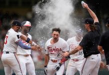 Minnesota Twins' Brooks Lee (2) celebrates with teammates after reaching on a winning infield RBI bunt to score teammate Byron Buxton during the ninth inning of a baseball game against the Tampa Bay Rays Saturday, July 5, 2025, in Minneapolis. (AP Photo/Abbie Parr)