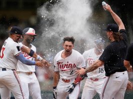 Minnesota Twins' Brooks Lee (2) celebrates with teammates after reaching on a winning infield RBI bunt to score teammate Byron Buxton during the ninth inning of a baseball game against the Tampa Bay Rays Saturday, July 5, 2025, in Minneapolis. (AP Photo/Abbie Parr)