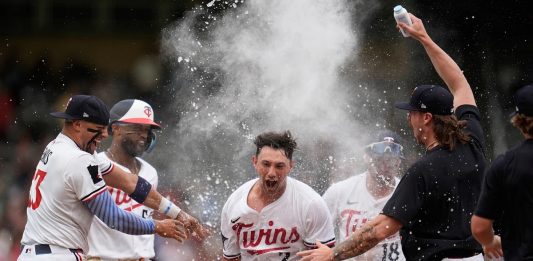 Minnesota Twins' Brooks Lee (2) celebrates with teammates after reaching on a winning infield RBI bunt to score teammate Byron Buxton during the ninth inning of a baseball game against the Tampa Bay Rays Saturday, July 5, 2025, in Minneapolis. (AP Photo/Abbie Parr)