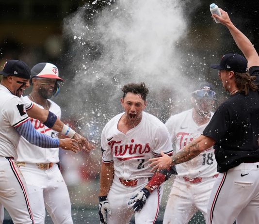 Minnesota Twins' Brooks Lee (2) celebrates with teammates after reaching on a winning infield RBI bunt to score teammate Byron Buxton during the ninth inning of a baseball game against the Tampa Bay Rays Saturday, July 5, 2025, in Minneapolis. (AP Photo/Abbie Parr)