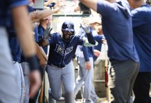 Tampa Bay Rays' Junior Caminero is greeted by teammates in the dugout after hitting a home run during the third inning of a baseball game against the Los Angeles Angels Wednesday, Aug. 6, 2025, in Anaheim, Calif. (AP Photo/William Liang)