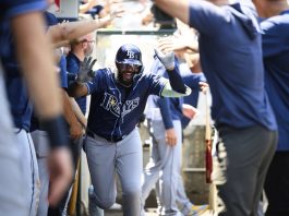 Tampa Bay Rays' Junior Caminero is greeted by teammates in the dugout after hitting a home run during the third inning of a baseball game against the Los Angeles Angels Wednesday, Aug. 6, 2025, in Anaheim, Calif. (AP Photo/William Liang)