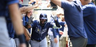 Tampa Bay Rays' Junior Caminero is greeted by teammates in the dugout after hitting a home run during the third inning of a baseball game against the Los Angeles Angels Wednesday, Aug. 6, 2025, in Anaheim, Calif. (AP Photo/William Liang)