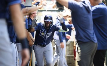 Tampa Bay Rays' Junior Caminero is greeted by teammates in the dugout after hitting a home run during the third inning of a baseball game against the Los Angeles Angels Wednesday, Aug. 6, 2025, in Anaheim, Calif. (AP Photo/William Liang)
