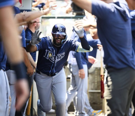 Tampa Bay Rays' Junior Caminero is greeted by teammates in the dugout after hitting a home run during the third inning of a baseball game against the Los Angeles Angels Wednesday, Aug. 6, 2025, in Anaheim, Calif. (AP Photo/William Liang)