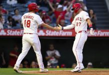 Los Angeles Angels' Mike Trout, right, and Nolan Schanuel, left, greet each other after scoring during the third inning of a baseball game against the Tampa Bay Rays, Monday, Aug. 4, 2025, in Anaheim, Calif. (AP Photo/William Liang)