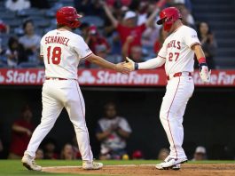 Los Angeles Angels' Mike Trout, right, and Nolan Schanuel, left, greet each other after scoring during the third inning of a baseball game against the Tampa Bay Rays, Monday, Aug. 4, 2025, in Anaheim, Calif. (AP Photo/William Liang)