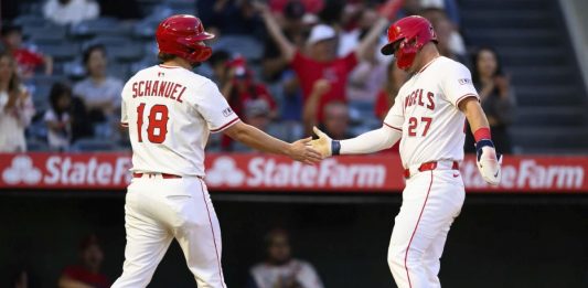 Los Angeles Angels' Mike Trout, right, and Nolan Schanuel, left, greet each other after scoring during the third inning of a baseball game against the Tampa Bay Rays, Monday, Aug. 4, 2025, in Anaheim, Calif. (AP Photo/William Liang)