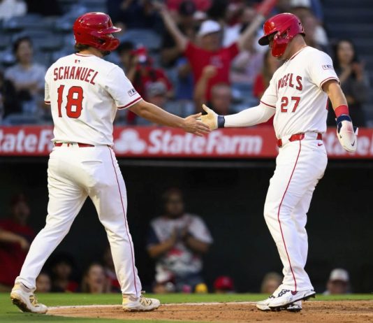 Los Angeles Angels' Mike Trout, right, and Nolan Schanuel, left, greet each other after scoring during the third inning of a baseball game against the Tampa Bay Rays, Monday, Aug. 4, 2025, in Anaheim, Calif. (AP Photo/William Liang)