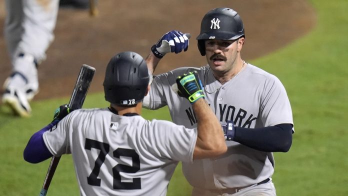 New York Yankees' Austin Wells (28) celebrates with José Caballero (72) after Wells hit a home run off Tampa Bay Rays pitcher Pete Fairbanks during the 10th inning of a baseball game Wednesday, Aug. 20, 2025, in Tampa, Fla. (AP Photo/Chris O'Meara)
