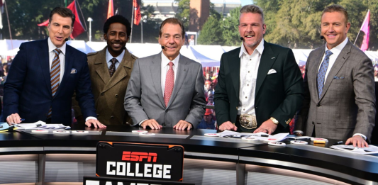 Nick Saban smiling on the ESPN College GameDay set in Tuscaloosa, wearing a suit and headset.